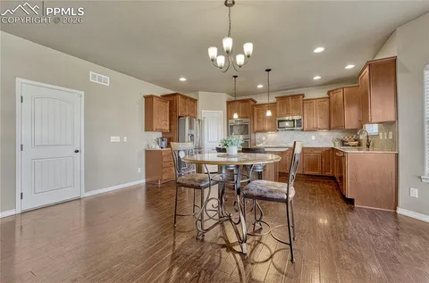 a kitchen with granite countertop a table chairs stove a sink and refrigerator