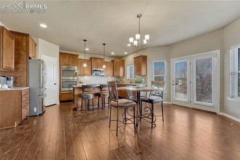 a view of a dining room and livingroom with furniture wooden floor a chandelier