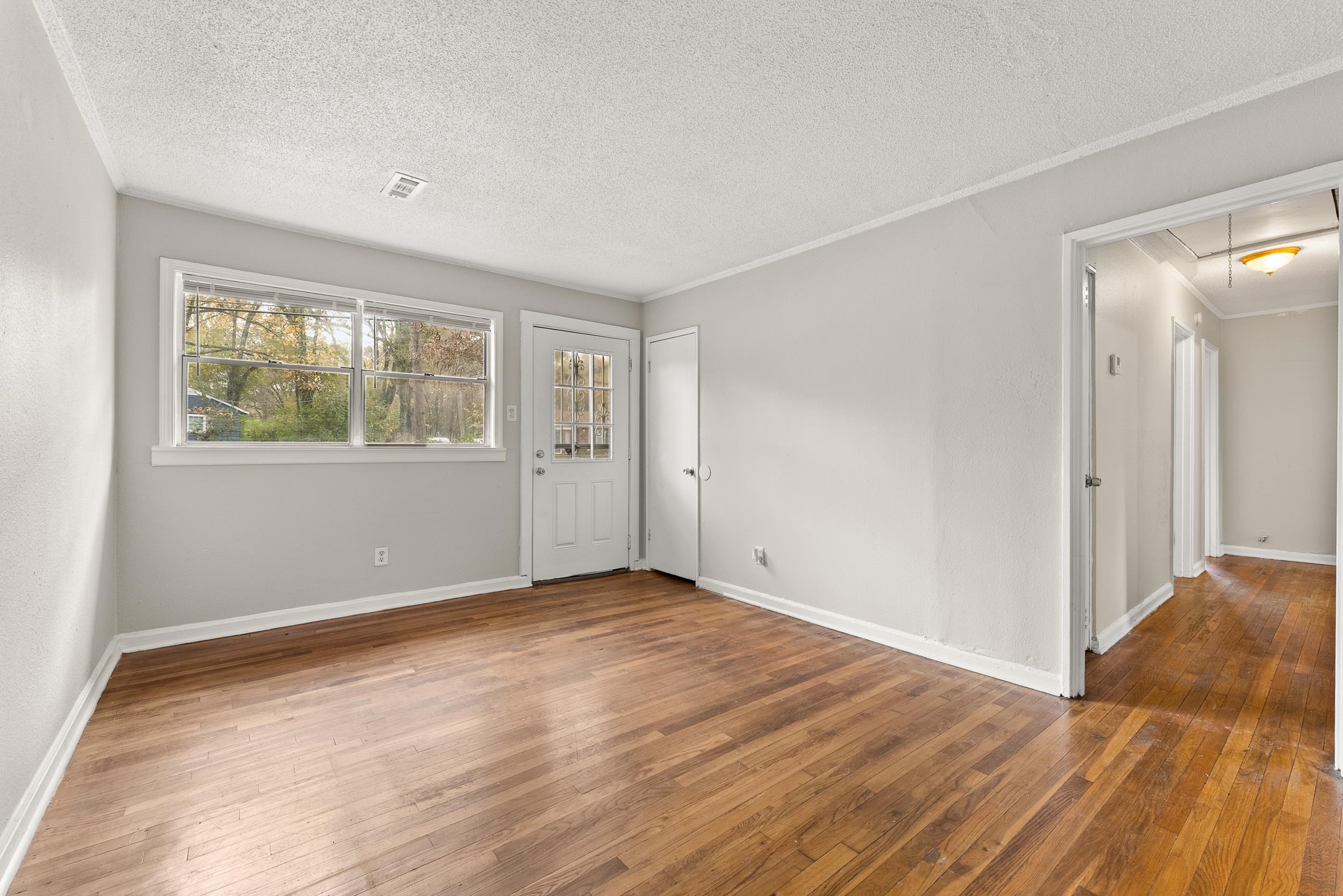 686 Delta Road Memphis, TN 38109 - Photo 3 of 24 a view of an empty room with wooden floor and a window
