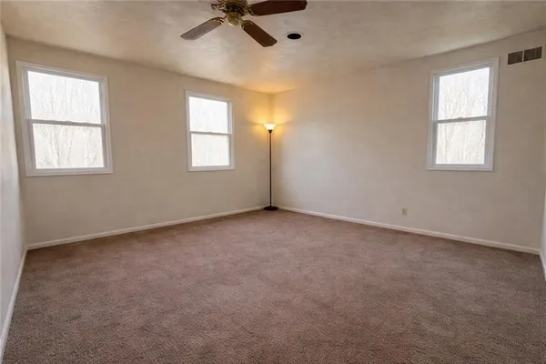 an empty room with windows and fan