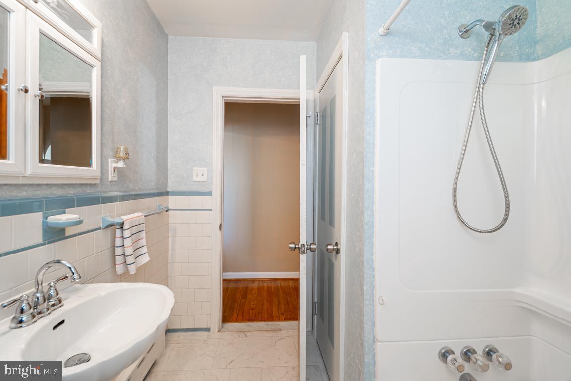 8504 Bassett Road Baltimore, MD 21237 - Photo 19 of 35 a bathroom with a sink a mirror and a shower
