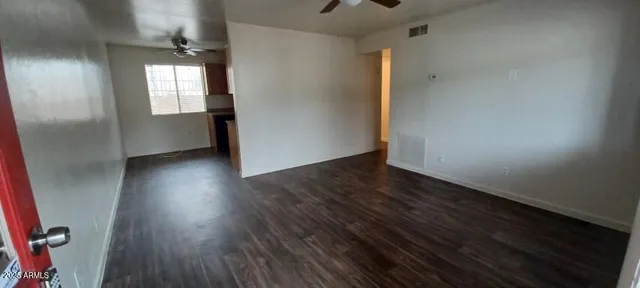 a view of an empty room with wooden floor and a window