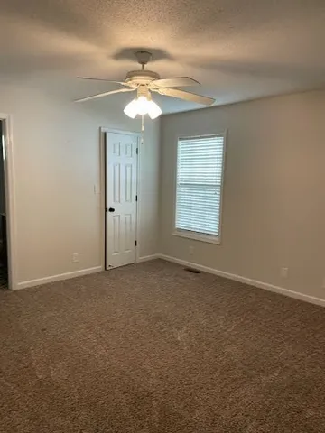 an empty room with windows and fan