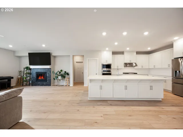 a large white kitchen with kitchen island a sink a stove a microwave a counter top and cabinets