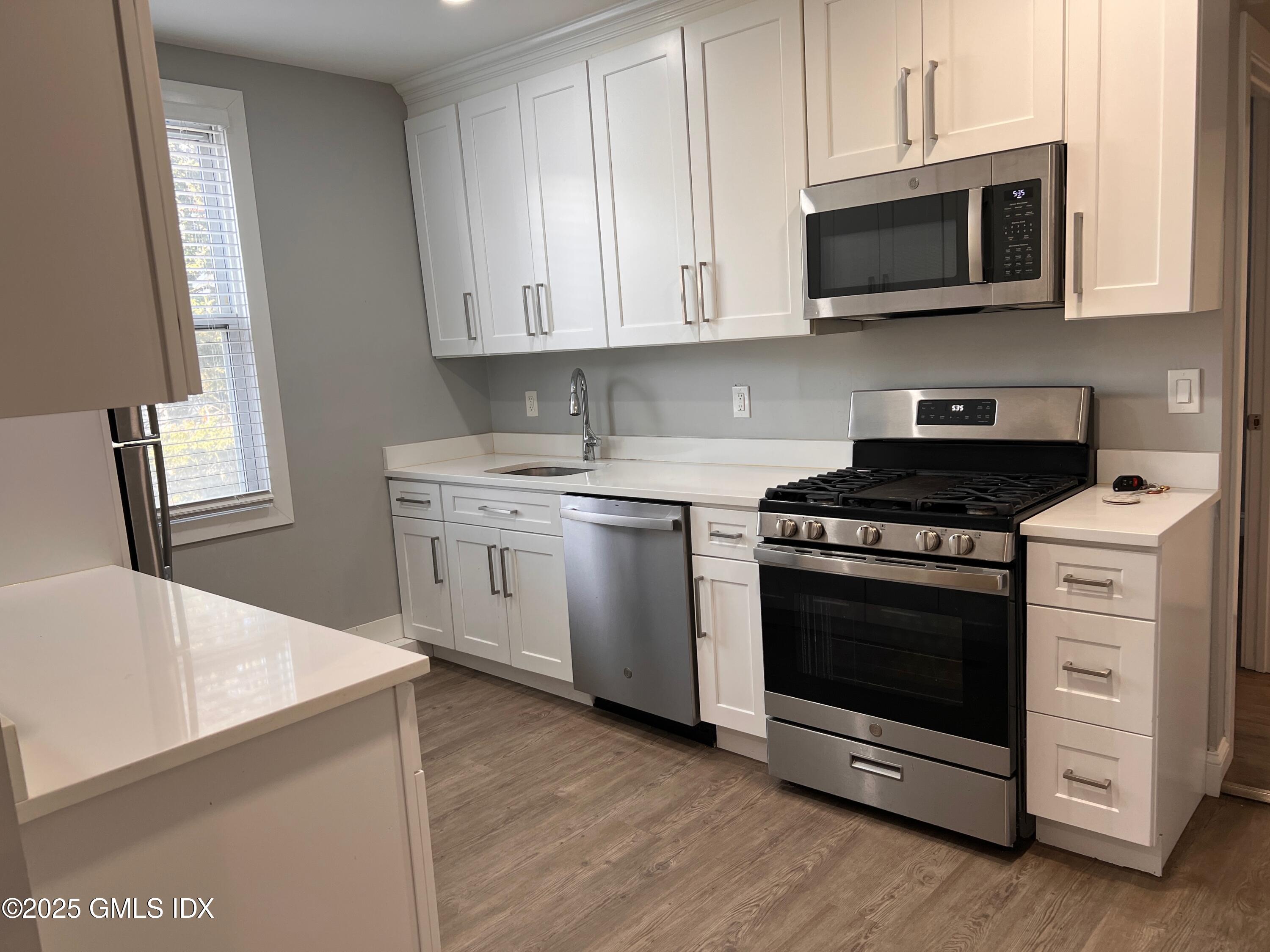 a kitchen with stainless steel appliances a stove microwave and sink
