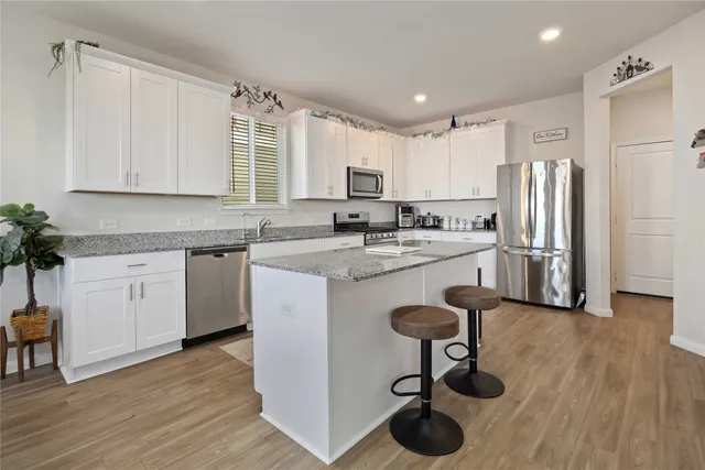 a kitchen with stainless steel appliances a sink a stove a refrigerator cabinets and wooden floor