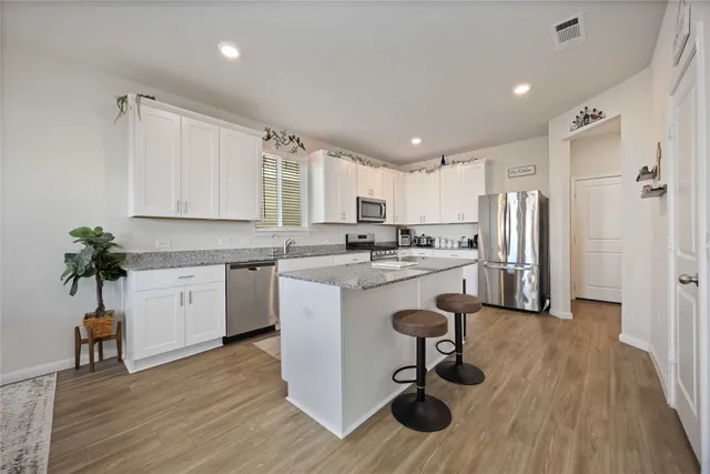 a kitchen with a refrigerator a white cabinets and wooden floor