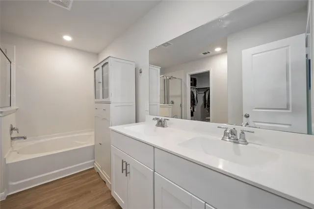 a bathroom with a sink double vanity granite tub shower and a mirror
