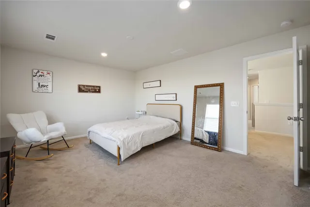 a spacious bedroom with a bed and chair