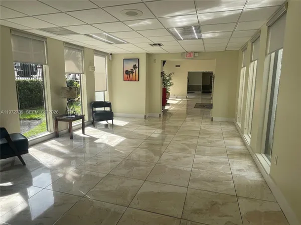a view of a hallway with wooden floor and a refrigerator