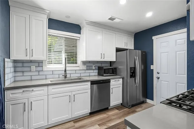 a kitchen with stainless steel appliances a refrigerator a sink a stove and cabinets