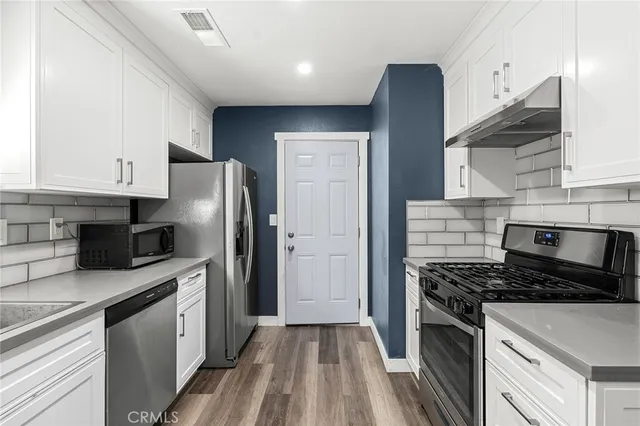 a kitchen with cabinets appliances and a wooden floor