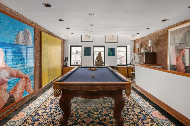 a room with wooden floor pool table and windows