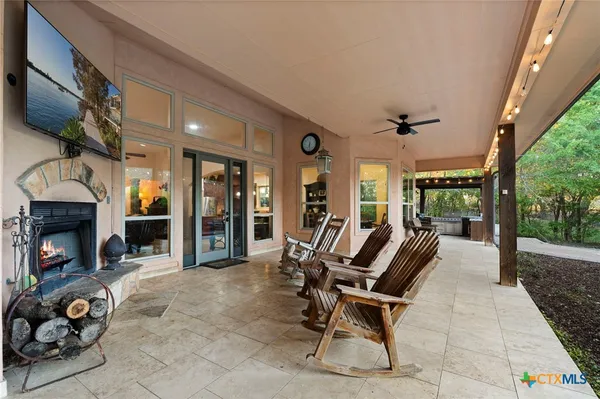 a view of a patio with table and chairs with a fireplace and floor to ceiling window