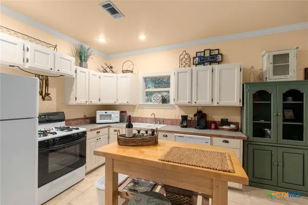 a kitchen with stainless steel appliances a stove a sink a refrigerator cabinets and furniture