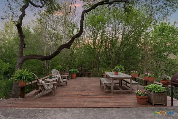 a view of a patio with couches table and chairs with potted plants and large trees