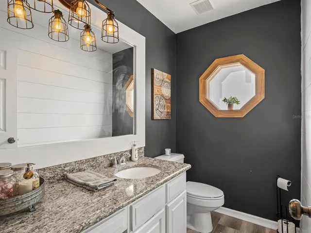 a bathroom with a granite countertop toilet and a sink