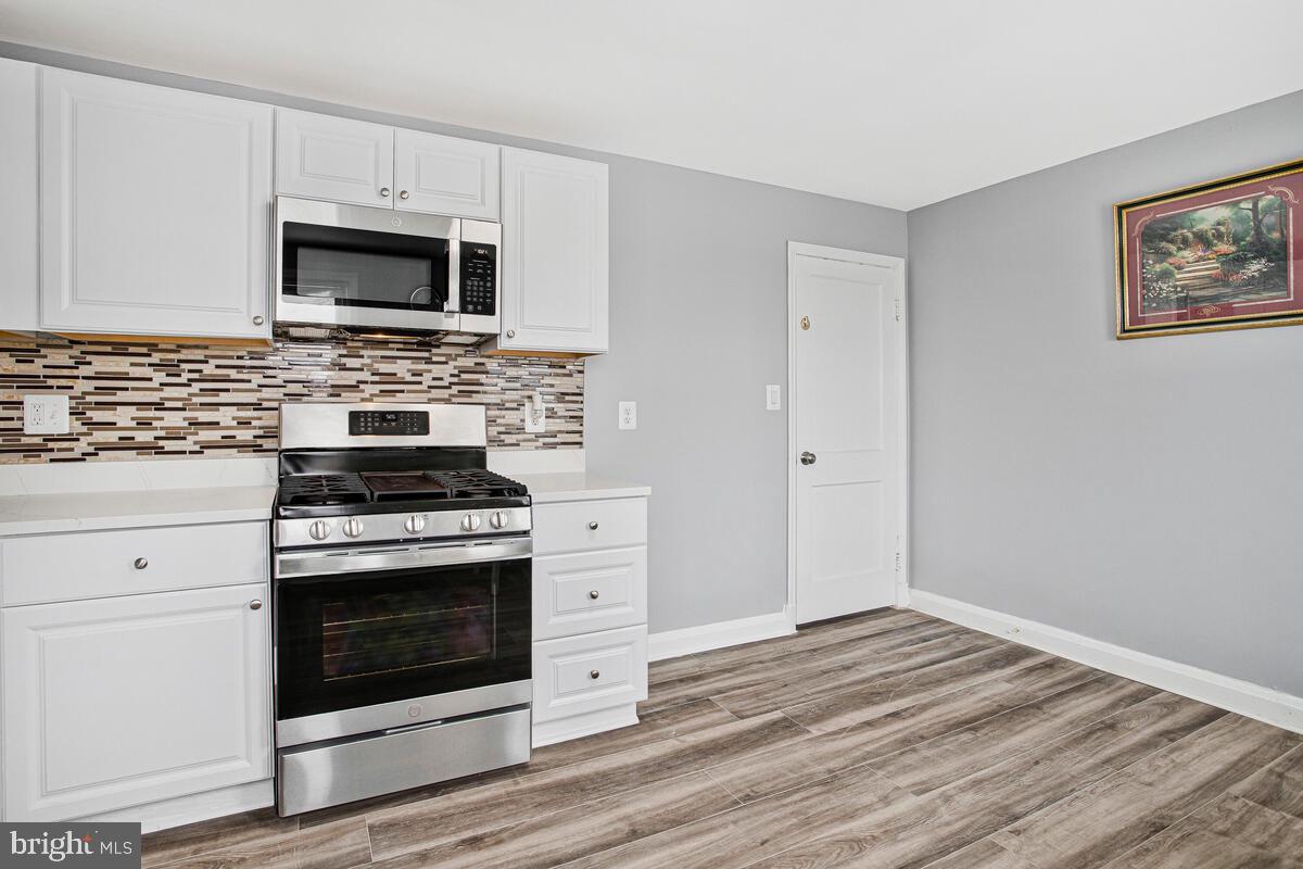 4004 Dudley Avenue Baltimore, MD 21213 - Photo 3 of 36 a kitchen with cabinets stainless steel appliances and wooden floor