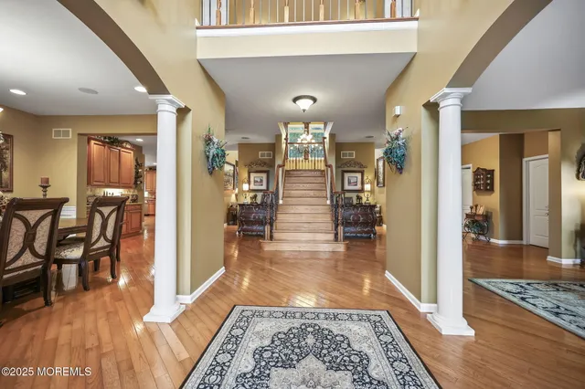 a kitchen with stainless steel appliances granite countertop a refrigerator a sink dishwasher a stove and a dining table with wooden floor