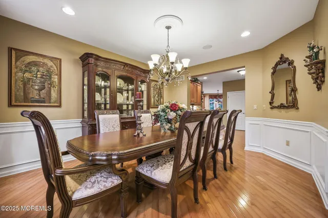 a kitchen with stainless steel appliances granite countertop a stove a sink dishwasher and a dining table with wooden floor