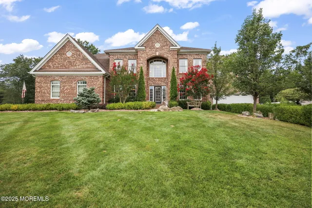 a view of a brick house with a big yard and large trees