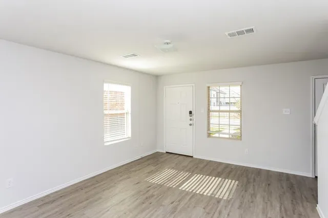a view of an empty room with a window and wooden floor