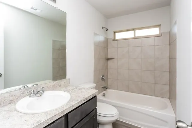 a bathroom with a granite countertop sink a toilet and bathtub