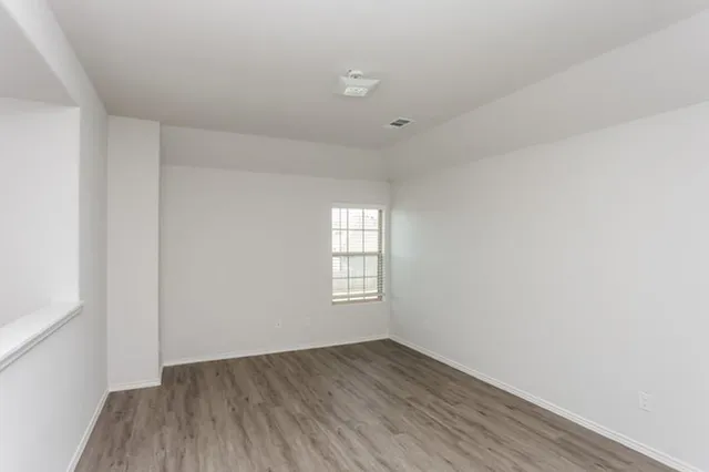 an empty room with wooden floor and window