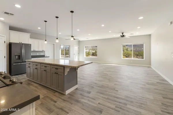 a large kitchen with stainless steel appliances granite countertop a large counter top a sink dishwasher a refrigerator and white cabinets with wooden floor