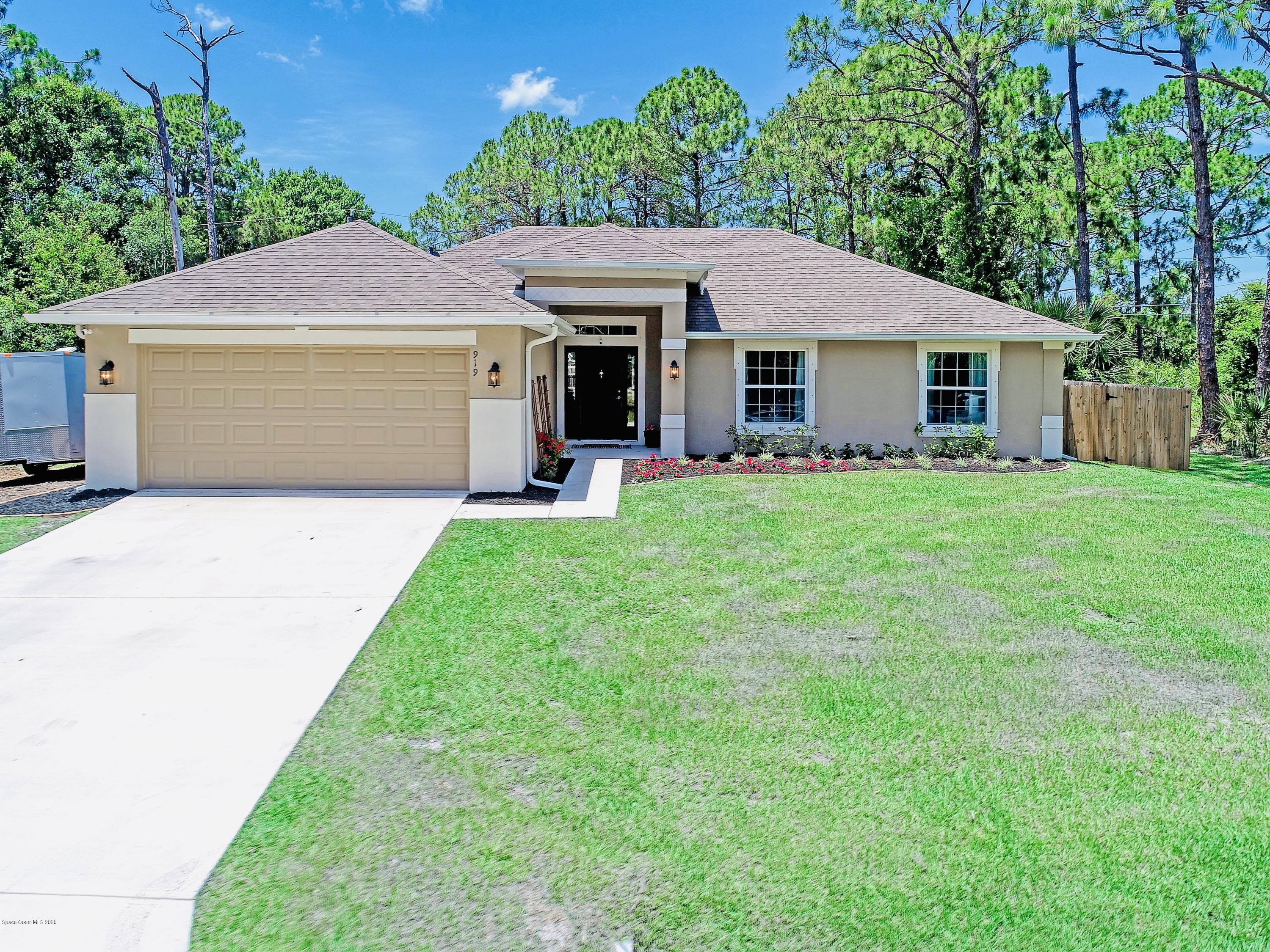 919 Thompson Road Southwest Palm Bay, FL 32908 - Photo 1 of 38 a front view of a house with a yard and garage