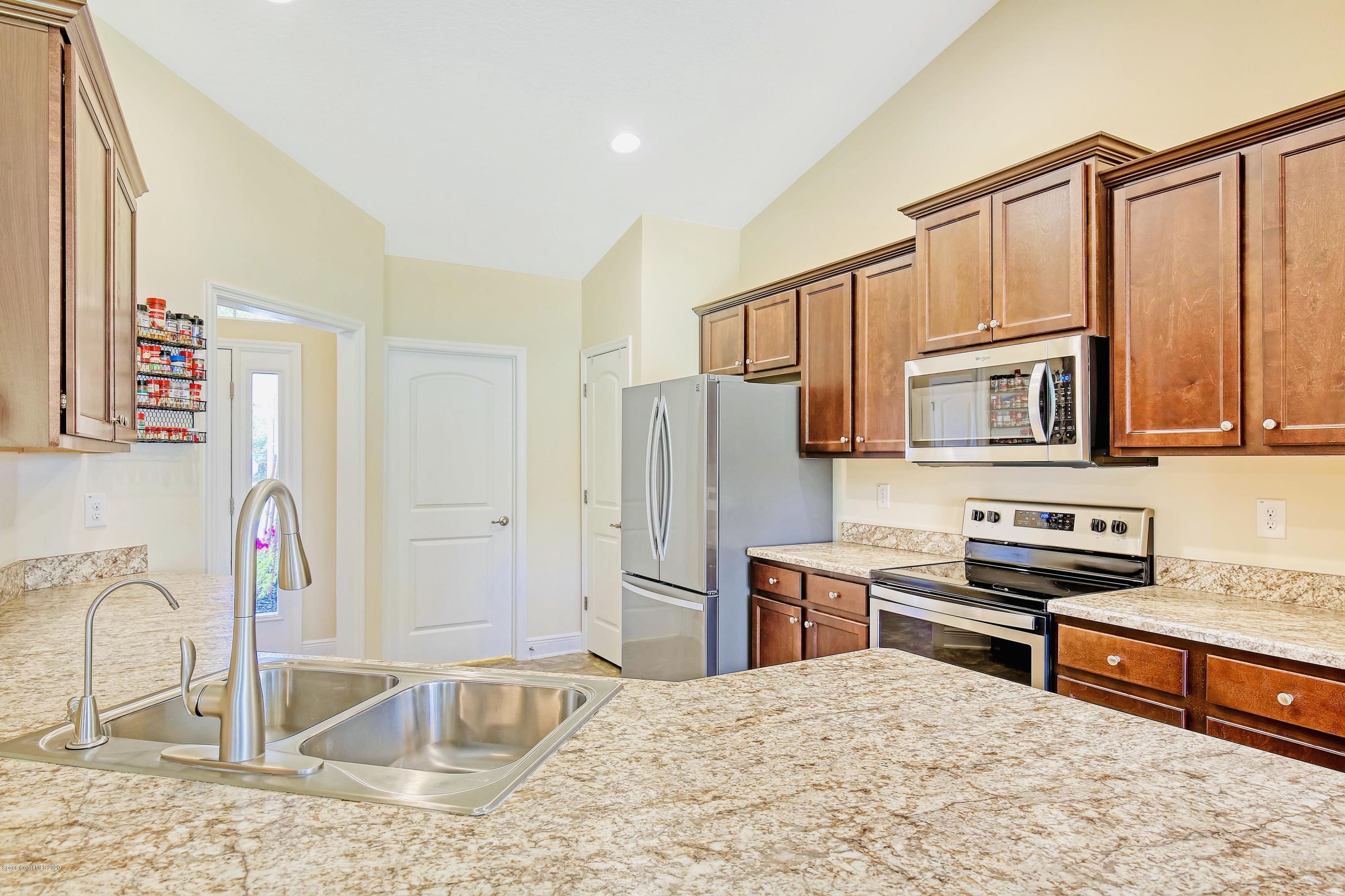 919 Thompson Road Southwest Palm Bay, FL 32908 - Photo 12 of 38 a kitchen with stainless steel appliances granite countertop a refrigerator stove and sink