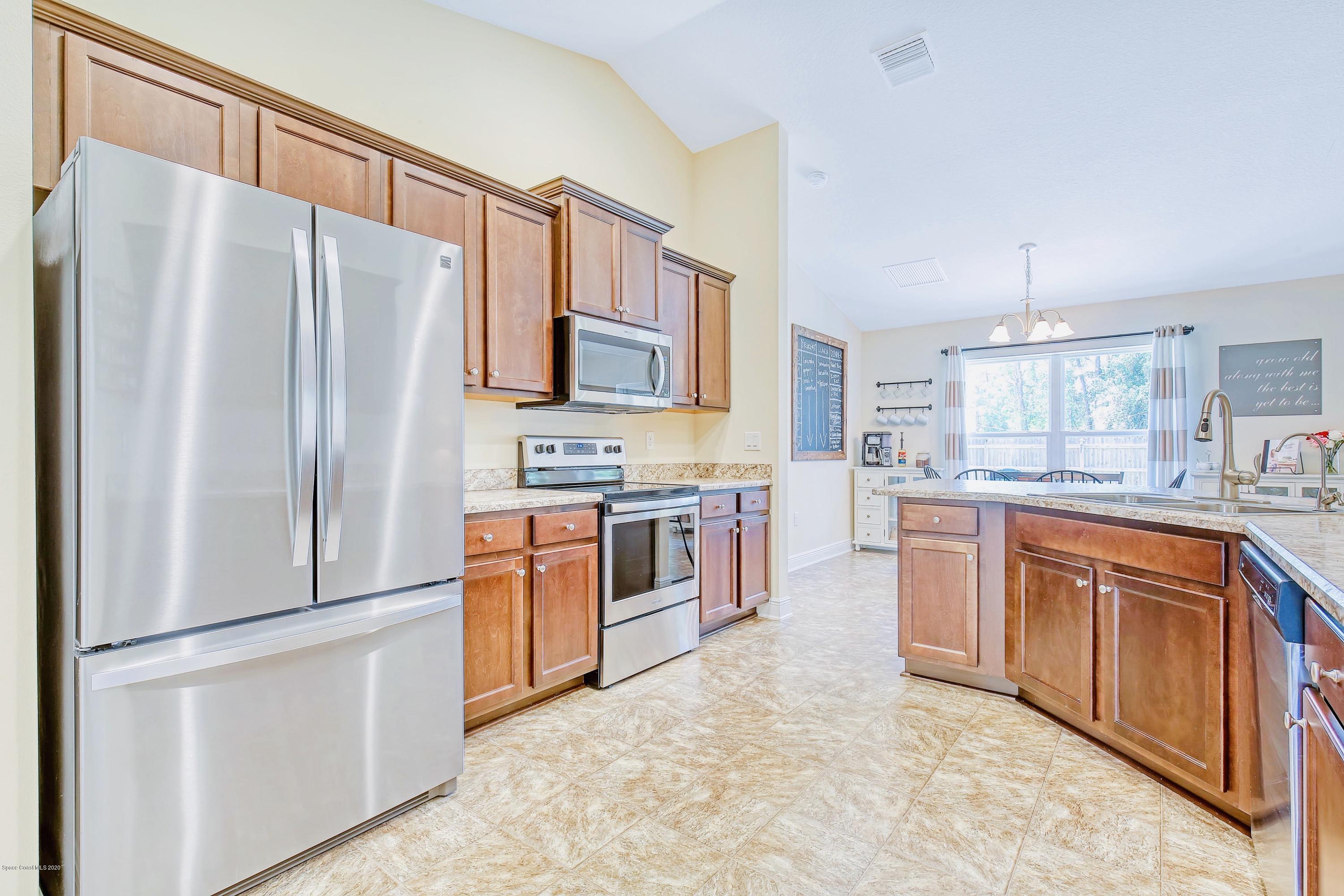 919 Thompson Road Southwest Palm Bay, FL 32908 - Photo 14 of 38 a kitchen with stainless steel appliances a refrigerator sink and cabinets