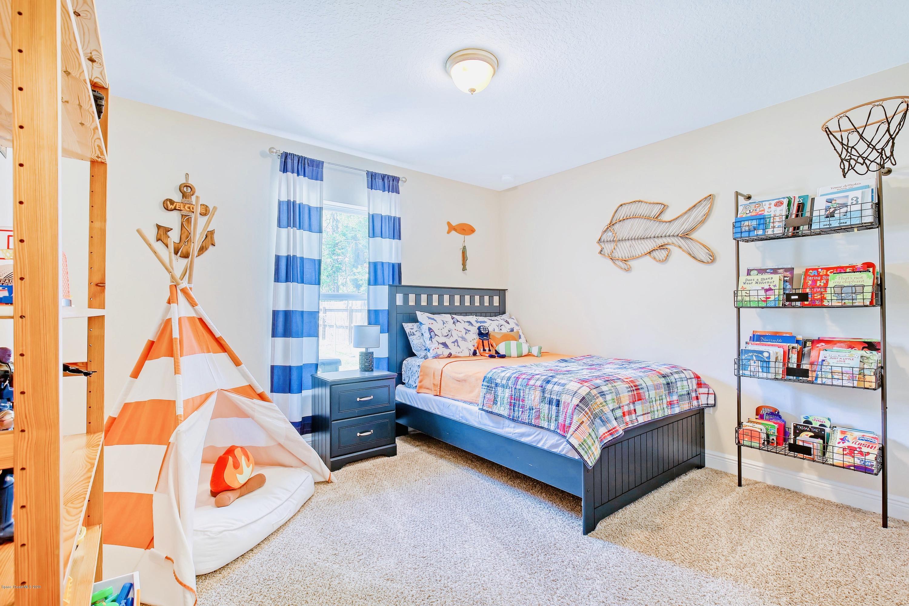 919 Thompson Road Southwest Palm Bay, FL 32908 - Photo 21 of 38 a bedroom with baby bed and a couch