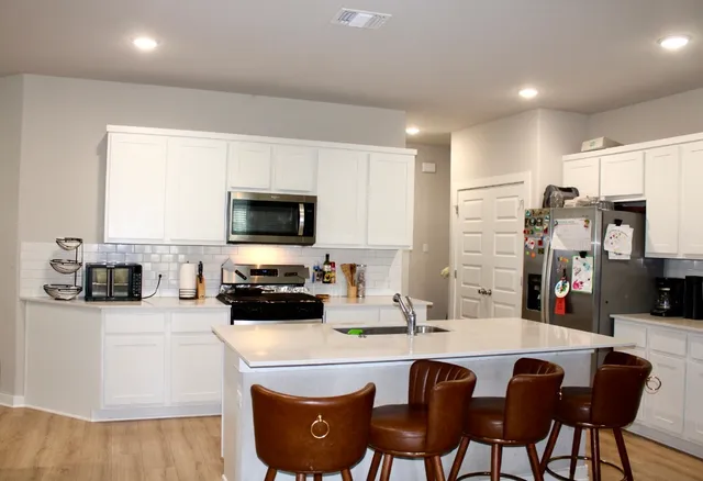 a kitchen with stainless steel appliances a stove a sink a microwave a refrigerator and cabinets