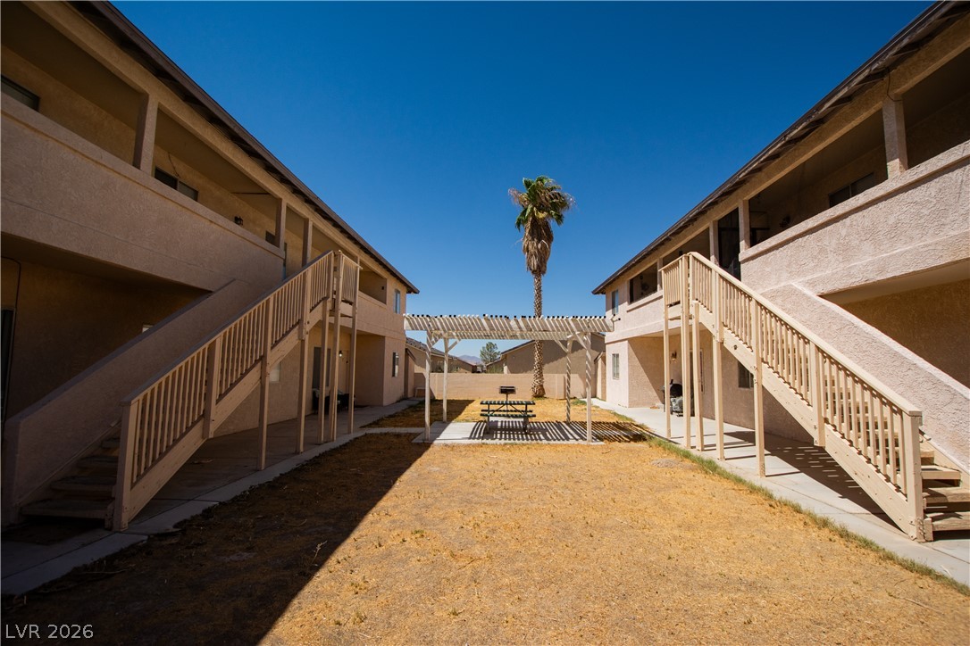 1444 Star Road Pahrump, NV 89048 - Photo 2 of 37 Stucco exteriors frame a central courtyard with a wooden pergola under open desert skies.