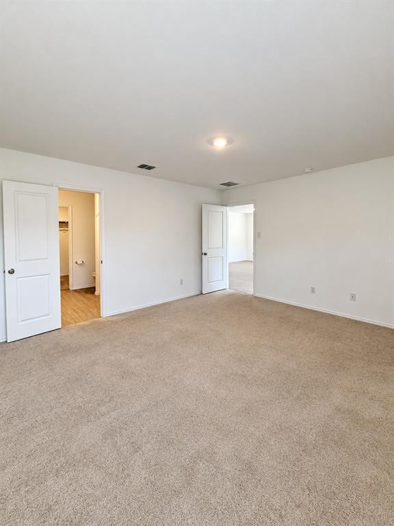 11726 Bone Spg Drive Rhome, TX 76078 - Photo 14 of 29 Spacious primary bedroom featuring neutral carpeting, recessed lighting, natural light, and direct access to the en-suite bathroom and walk-in closet.