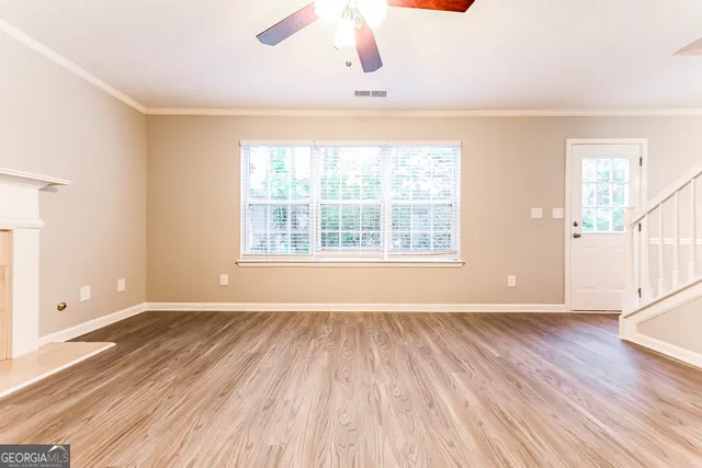an empty room with wooden floor cabinet and windows