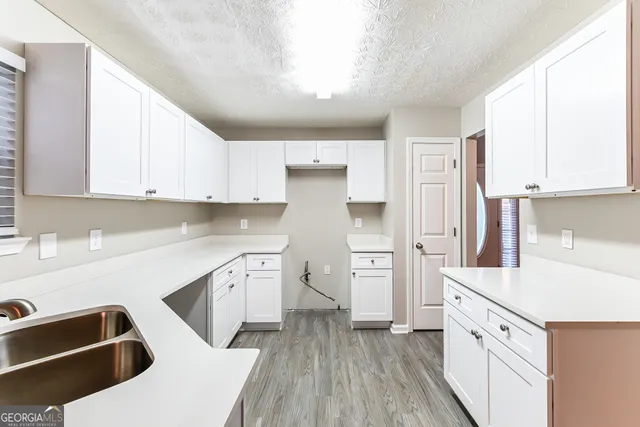 a kitchen with white cabinets and refrigerator