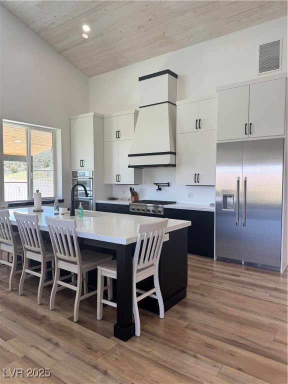 8946 Highway 93 Caliente, NV 89008 - Photo 7 of 40 Kitchen with high vaulted ceiling, white cabinets, fridge, light wood finished floors, and wooden ceiling