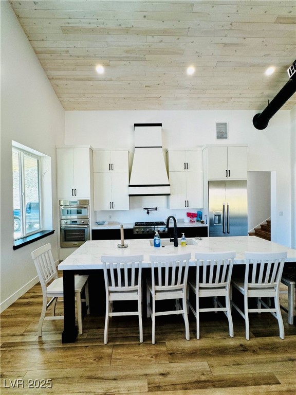 8946 Highway 93 Caliente, NV 89008 - Photo 8 of 40 Kitchen with white cabinets, a spacious island, light wood-type flooring, a breakfast bar area, and appliances with stainless steel finishes