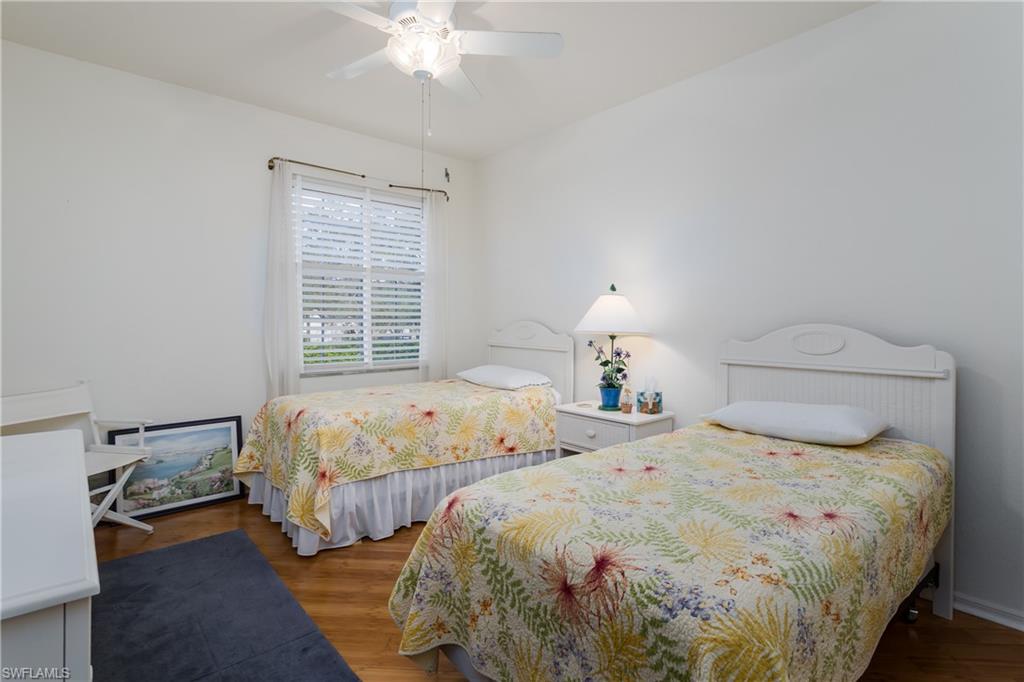 640 Lalique Circle, Unit 405 Naples, FL 34119 - Photo 27 of 49 a bedroom with two beds and a chandelier