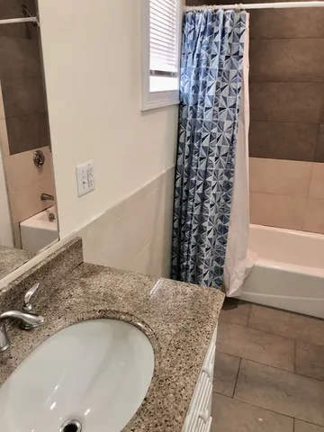 a bathroom with a granite countertop bathtub sink and shower