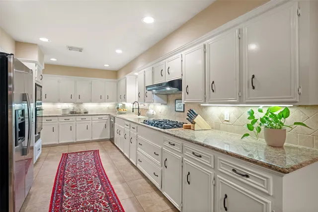 a kitchen with granite countertop white cabinets and white stainless steel appliances