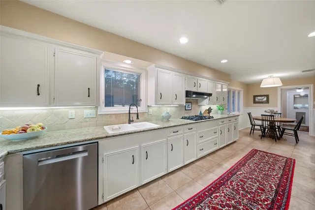 a kitchen with granite countertop sink a stove a dining table and chairs