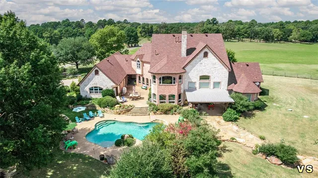 an aerial view of a house with outdoor space and trees all around