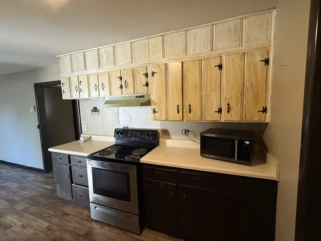 a kitchen with granite countertop a refrigerator a stove a sink and dishwasher with wooden floor