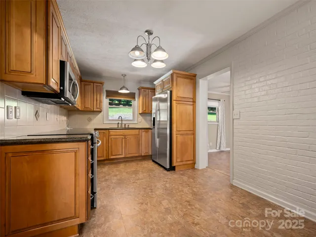 a kitchen with stainless steel appliances granite countertop a refrigerator a stove and a sink with cabinets