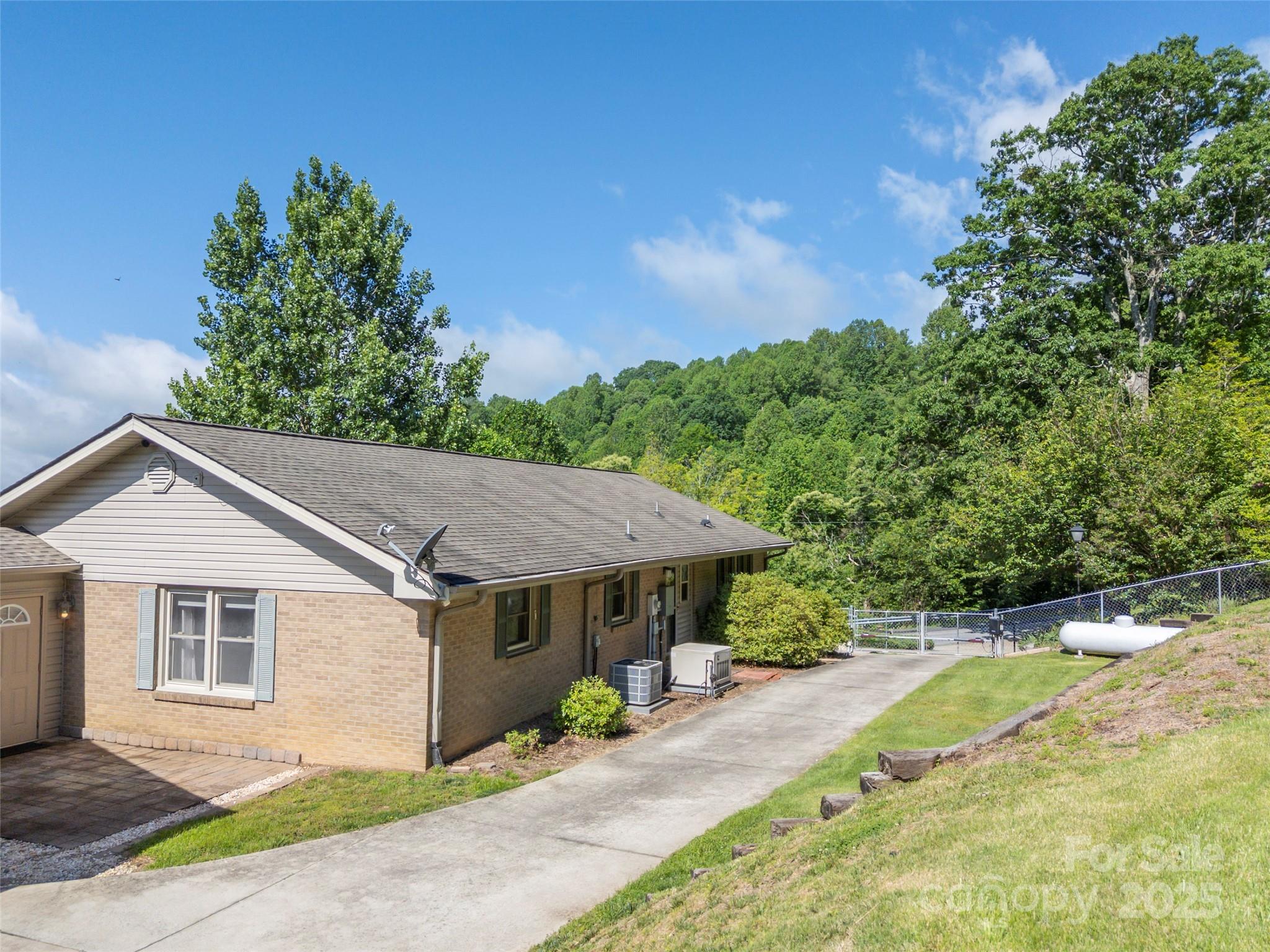 418 Mountain Page Road Saluda, NC 28773 - Photo 42 of 48 a view of a white house with a yard plants and large tree
