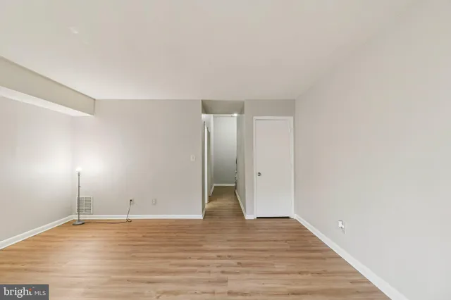 an empty room with wooden floor chandelier fan and windows
