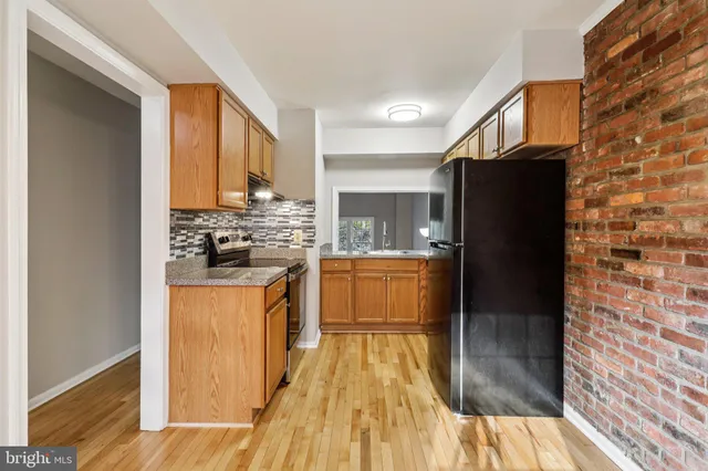 a view of a refrigerator in kitchen and an empty room